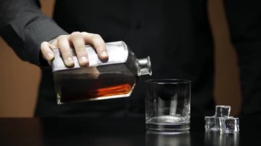 Viski, konyak ve buz küpleri. Barmen içki doldurur.