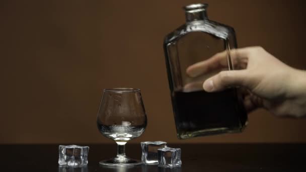 Pouring whiskey, cognac into glass. Dark background. Pour of alcohol drink — Stock Video