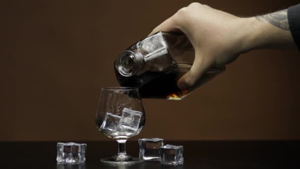 Pouring whiskey, cognac into glass. Dark background. Pour of alcohol drink — Stock Video