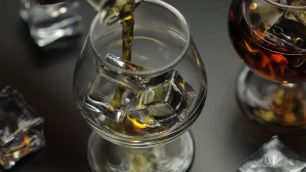 Whisky, cognac in glas met ijsblokjes. Schenk alcohol in. — Stockvideo