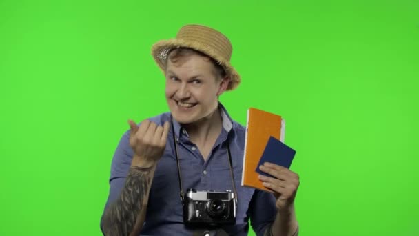 Retrato de hombre fotógrafo turístico con pasaporte y entradas agitando su mano — Vídeo de stock