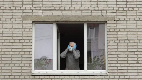 Old man grandfather stay at window isolated at home on quarantine. Coronavirus