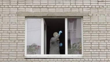 Gaz maskeli yaşlı adam karantinada yalnız başına pencerede dans ediyor. Coronavirüs
