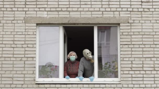 Los abuelos viejos se quedan en la ventana aislados en casa en cuarentena. Coronavirus — Vídeos de Stock