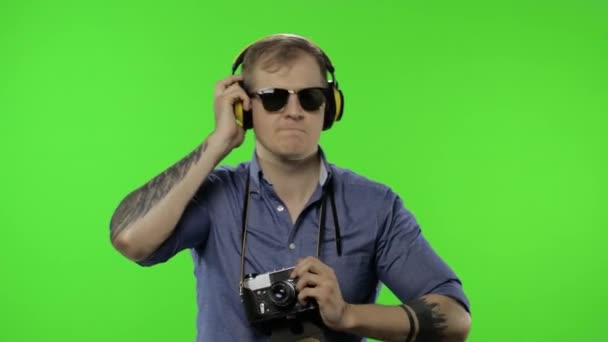 Retrato de hombre feliz fotógrafo turístico con auriculares bailando. Clave de croma — Vídeos de Stock