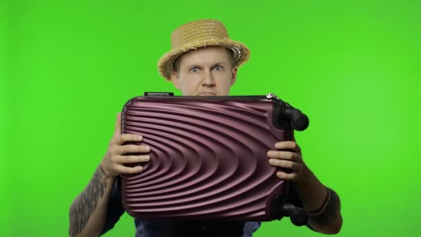 Een portret van een toerist verstopt zich achter een koffer en kijkt uit. Chromatoetsen — Stockvideo