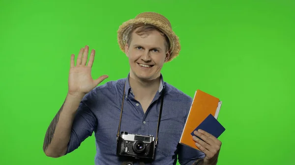 Retrato de hombre fotógrafo turístico con pasaporte y entradas agitando su mano — Foto de Stock