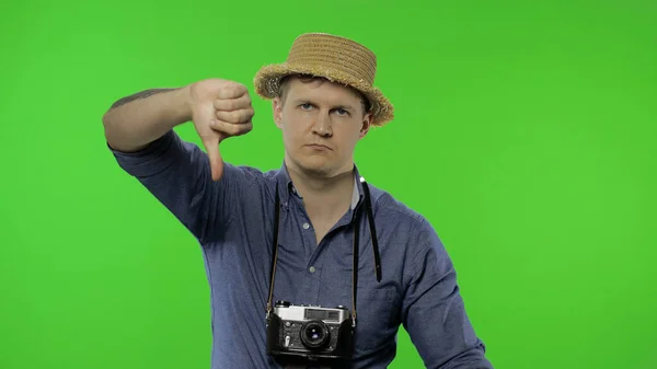 Retrato de jovem fotógrafo turístico dando polegares para baixo. Chave Chroma — Fotografia de Stock