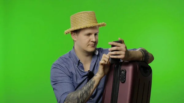 Portret turysty z walizką przy użyciu telefonu komórkowego, czat. Klucz chromowy — Zdjęcie stockowe