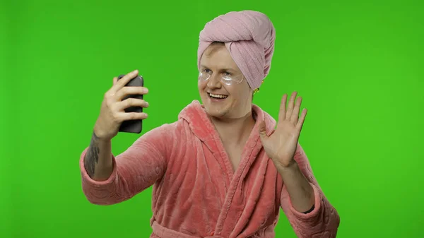 Retrato de hombre transexual en albornoz usando teléfono móvil para videollamada —  Fotos de Stock