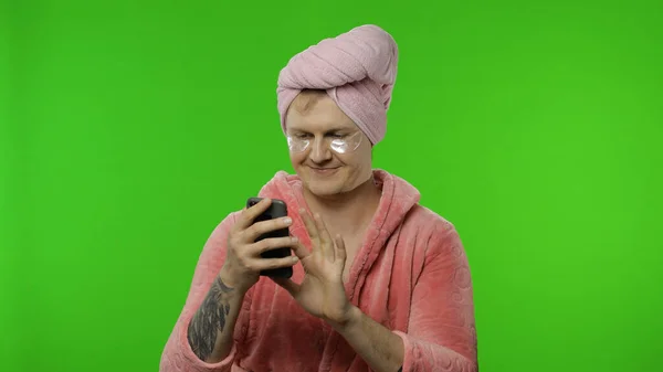 Bornoz giymiş transseksüel bir adamın portresi. Sohbet etmek için cep telefonu kullanıyor, çalışıyor. — Stok fotoğraf