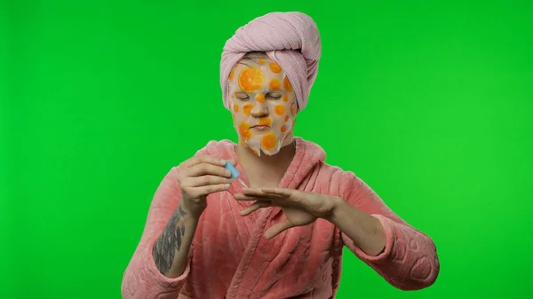 Homme transsexuel en peignoir avec masque facial peignant ses ongles de main. Clé chromatique — Photo