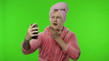 Video görüşmesi için cep telefonu kullanan bornozlu bir transseksüel portresi.
