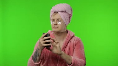 Bornoz giymiş transseksüel bir adamın portresi. Sohbet etmek için cep telefonu kullanıyor, çalışıyor.