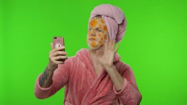 Yüz maskeli transseksüel adam video görüşmesi için cep telefonunu kullanıyor.