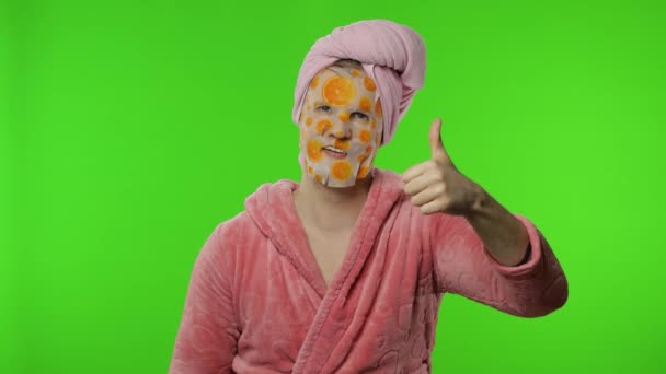 Homem transexual em roupão de banho com máscara facial dando polegares para cima. Chave Chroma — Vídeo de Stock