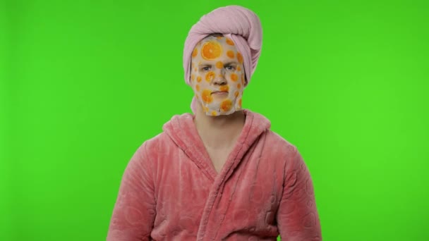 Transseksualista w szlafroku z maską na twarzy macha ręką, podnosząc kciuki — Wideo stockowe