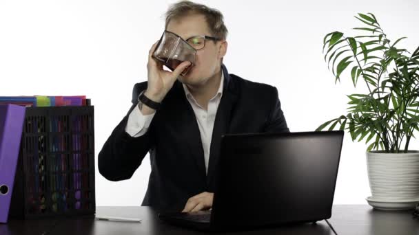 Уставший разъеденный бизнесмен усердно работает в офисе и пьет алкогольный коньяк — стоковое видео