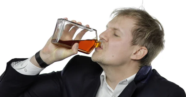 Um jovem e sonolento empresário cansado. Deprimido trabalhador desgrenhado beber álcool conhaque — Fotografia de Stock