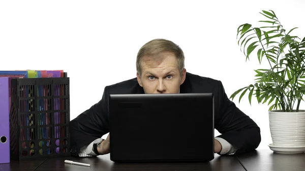 ビジネスマンマネージャーはノートパソコンの後ろに隠し、オフィスで働いている間外を見る — ストック写真
