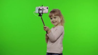 Kız çocuğu selfie çekiyor, cep telefonunda selfie çubuğu kullanıyor. Krom anahtar