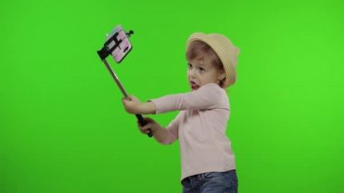 Kız çocuğu selfie çekiyor, cep telefonunda selfie çubuğu kullanıyor. Krom anahtar