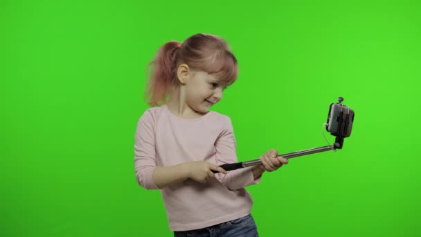 Girl child makes selfie, blogging on mobile phone using selfie stick. Chroma key — Stock Video