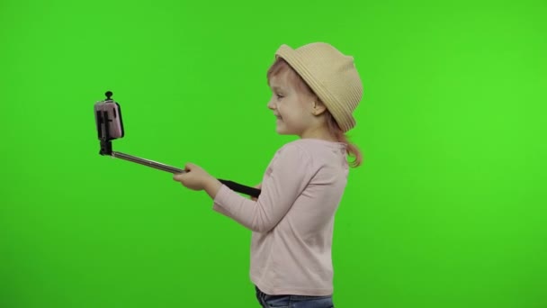 Girl child makes selfie, blogging on mobile phone using selfie stick. Chroma key — Stock Video