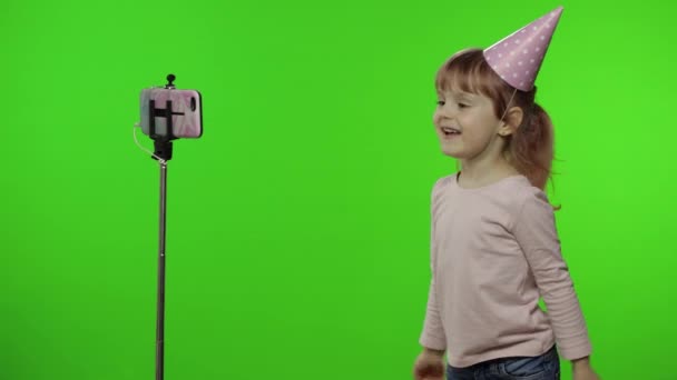 Menina criança faz selfie vlog, blogging, vídeo call on mobile phone using monopod — Vídeo de Stock