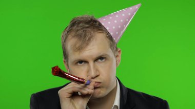 Şenlik şapkası takmış sarhoş, dağılmış genç iş adamı düdük çalıyor. Akşamdan kalma.