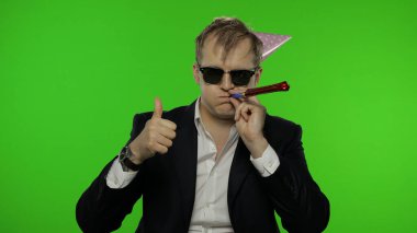 Şenlik şapkasıyla akşamdan kalma sarhoş genç işadamı başparmağını kaldırıyor.