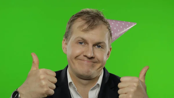 Drunk sleepy young businessman with hangover in festive cap giving thumbs up — Stock Photo, Image