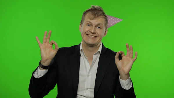 Drunk sleepy young businessman with hangover in festive cap showing OK sign — Stock Photo, Image