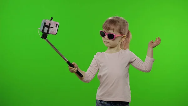 여자 아이는 셀카를 만들고, 셀카 스틱을 사용하여 휴대폰으로 블로 깅을합니다. 크로마 키 — 스톡 사진