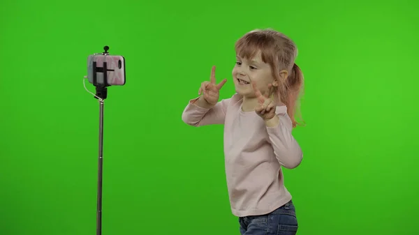 Kız çocuğu monopod kullanarak selfie vlog, blog, video çağrısı yapıyor. — Stok fotoğraf