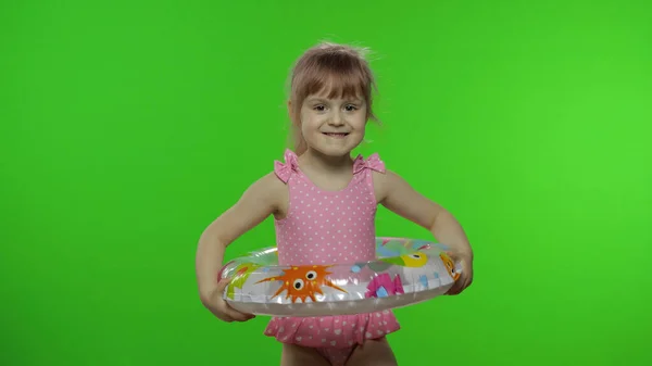 Enfant drôle fille en maillot de bain marche avec anneau de natation, faire des visages. Vacances — Photo