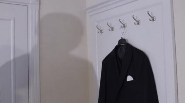 Beyaz gömlekli damat geldi ve evdeki askıdan siyah ceketini çıkardı.