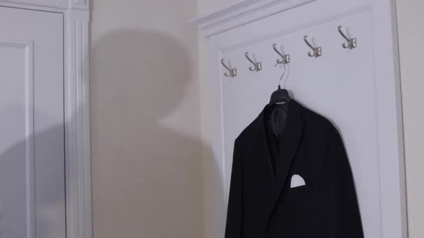 Groom dans une chemise blanche vient et enlève sa veste noire du cintre à la maison — Video