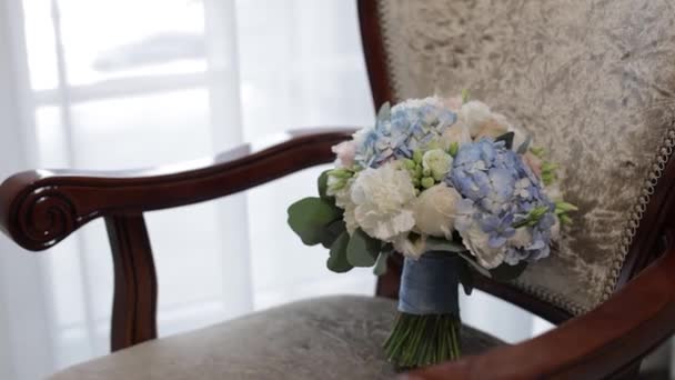 Bukiet białych róż i niebieskich kwiatów. Bukiet ślubny panny młodej na krześle — Wideo stockowe