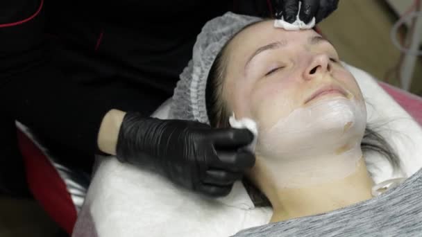 Cosmetólogo limpia clien mujer cara de mascarilla hidratante en salón de belleza — Vídeo de stock