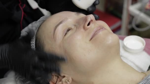 Косметолог наносить зволожуючий крем на обличчя жінки в салоні краси — стокове відео