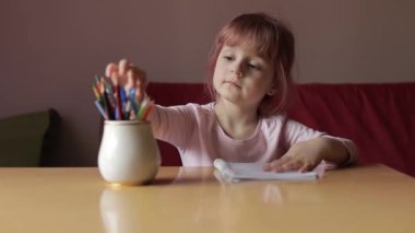 Sevimli çocuk ressam evde kalem ve kalemle resim çiziyor.