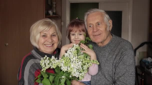 Nieta abraza anciano sonriente abuelo con la abuela en casa — Vídeos de Stock