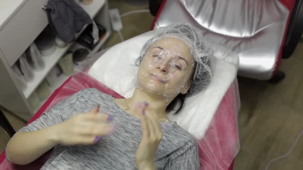 Retrato de mujer en salón de belleza clínica. Chica con máscara en la cara con espuma jabonosa — Vídeos de Stock