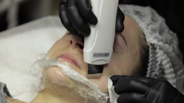 Cosmetólogo hacer limpieza facial ultrasónica en la cara de la mujer en el salón de belleza clínica — Vídeo de stock