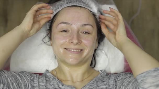 Portrait de femme dans un salon de beauté. Fille avec masque hydratant sur le visage — Video