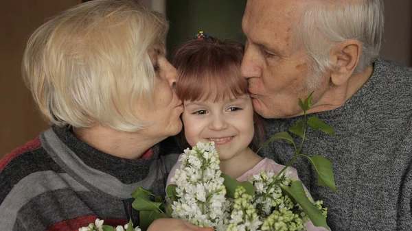 Abuelo y abuela besándose en la cabeza a su nieta en casa — Foto de Stock