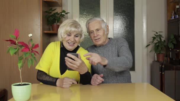 Vrij volwassen senior paar grootouders het maken van video gesprek met telefoon thuis — Stockvideo