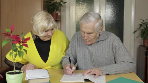 Щаслива стара зріла пара на пенсії сидить на столі вдома насолоджуючись вільним дозвіллям — стокове відео