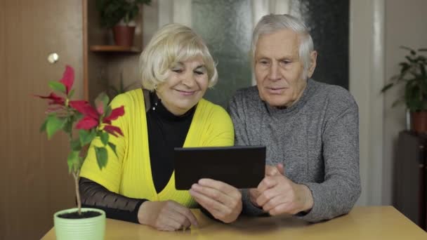 Vrij volwassen senior paar grootouders genieten van online winkelen op tablet thuis — Stockvideo